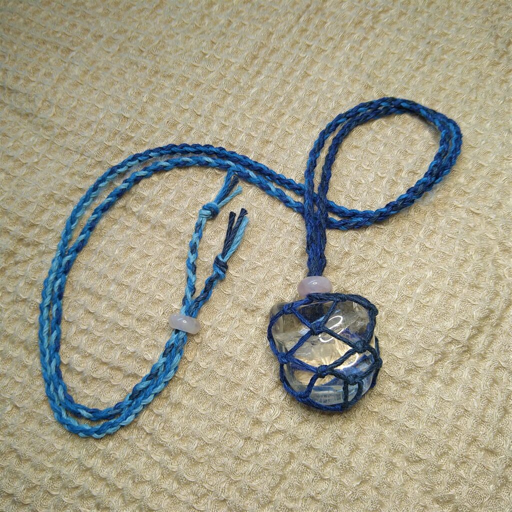 Blue macrame crystal necklace. Handmade gemstone jewelry with woven cord and clear quartz.