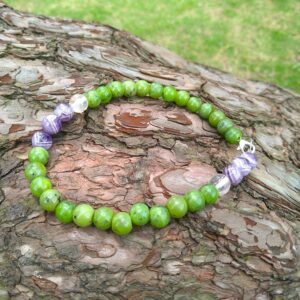 Green jade beaded bracelet with amethyst and clear quartz accents on bark. Handmade jewelry.